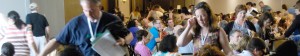 Volunteers pass around material in a conference room packed with people.