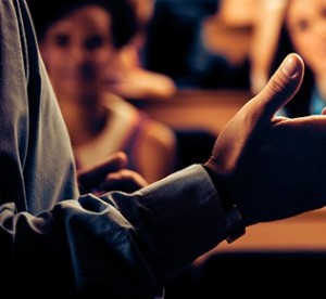 teacher gesturing hands with students in background