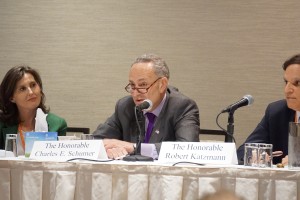 U.S. Senator Charles Schumer seated and speaking into a microphone at the "Congress and Courts" session