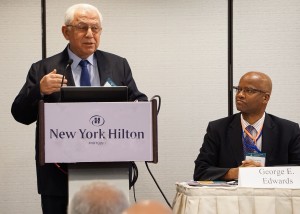Haluk Kabaalioglu standing behind podium and George E. Edwards watching at the US and Overseas Partnerships panel