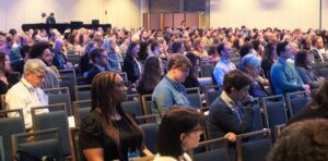 Crowd sits taking notes during a session