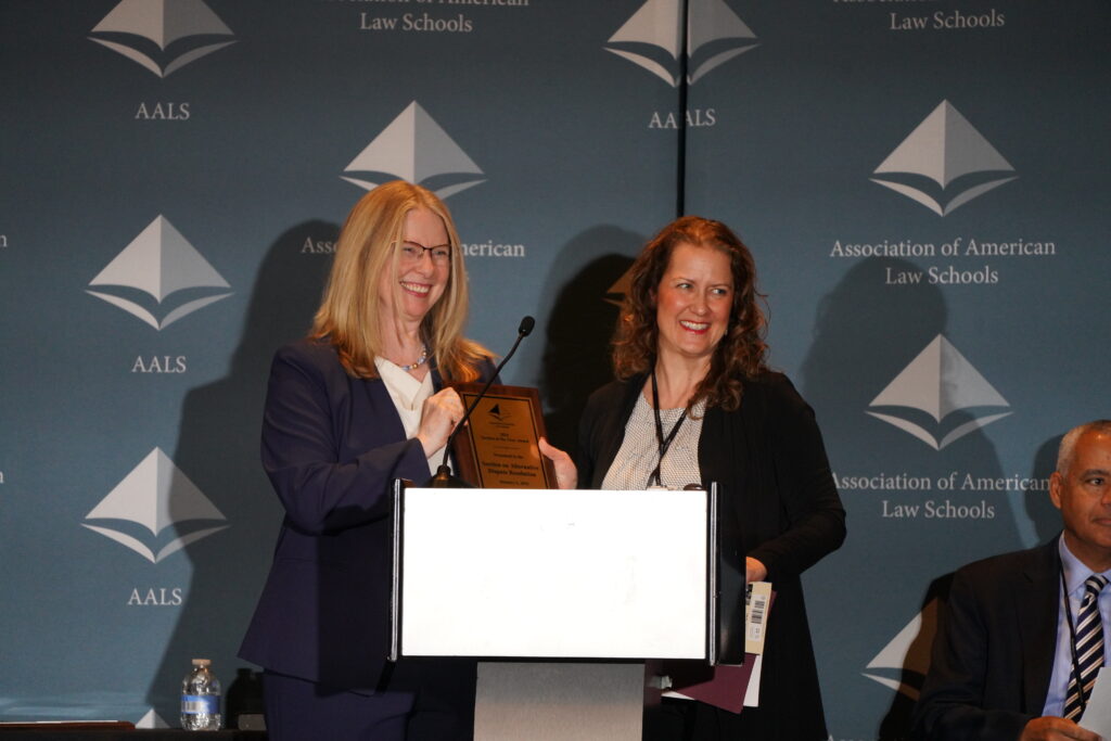 Two award recipients speaking at a podium