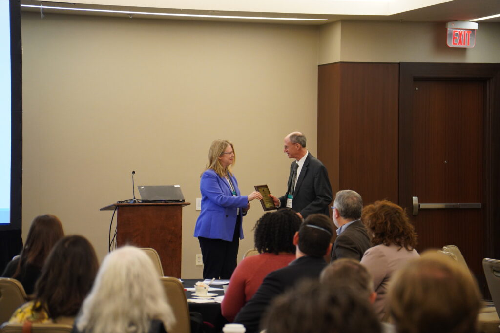 Two people shaking hands in front of crowd at awards ceremony