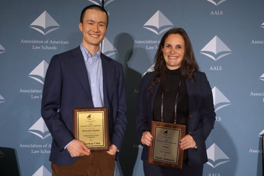 Two smiling people holding their plaques at a conference